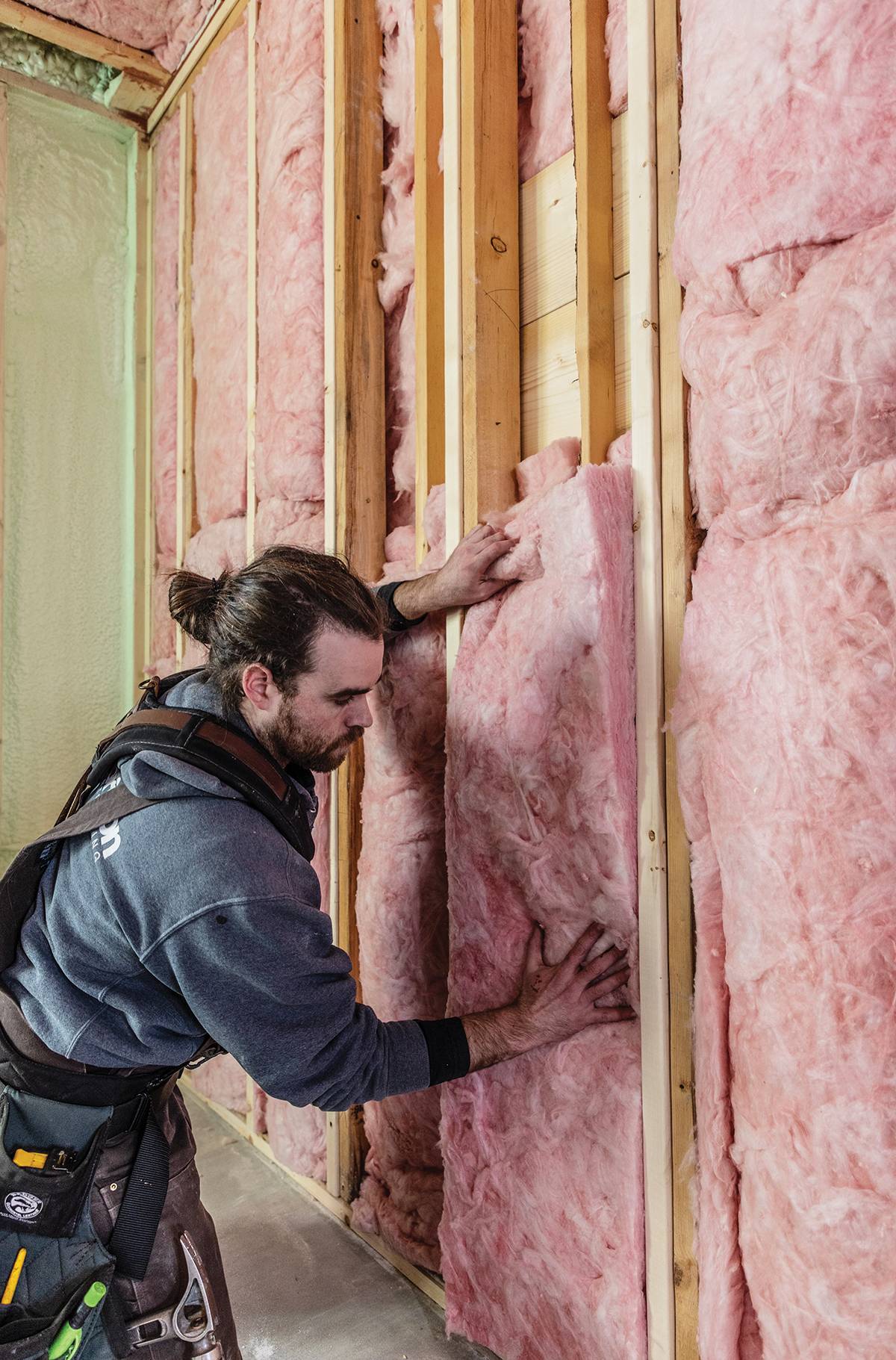 Worker installing pink insulation